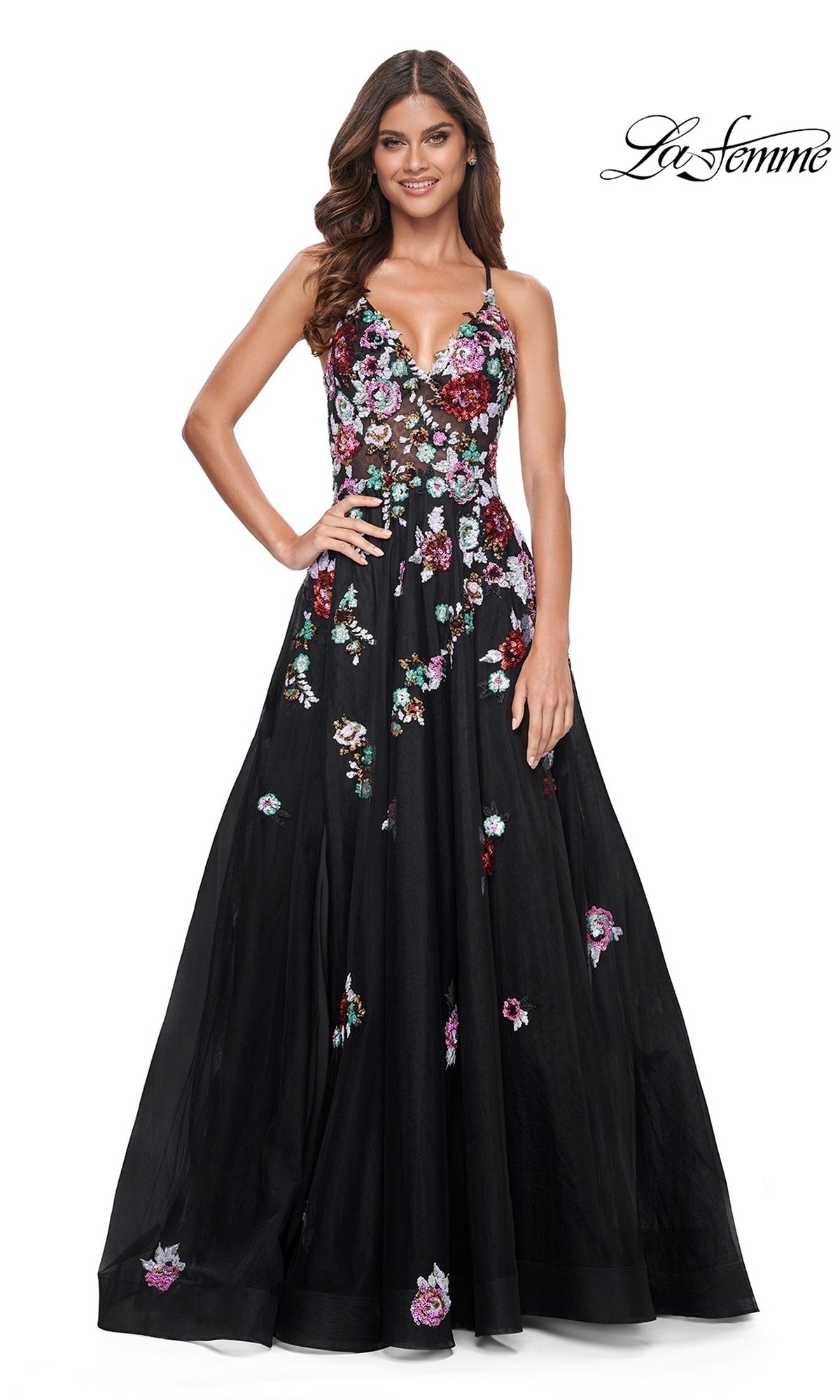 A woman stands and smiles against a white background, wearing the La Femme Floral-Sequin Long Black Prom Dress 32051 featuring a sleeveless design, colorful sequin flowers, and a fitted bodice. The